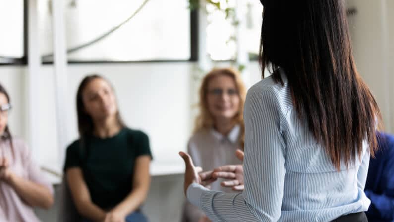 Rear back view of a lady discussing to her coworkers