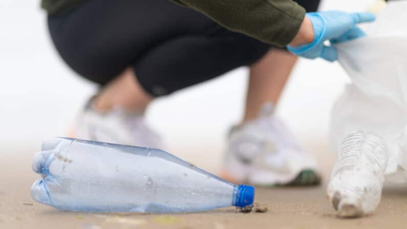 person picking up trash and debris on the shore